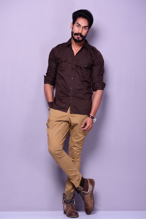 Free Handsome man in brown shirt and beige pants posing with elegance in portrait format. Stock Photo