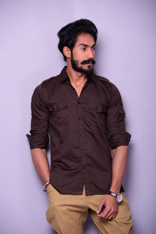 Free A fashionable man with a beard posing in a brown shirt against a purple background. Stock Photo