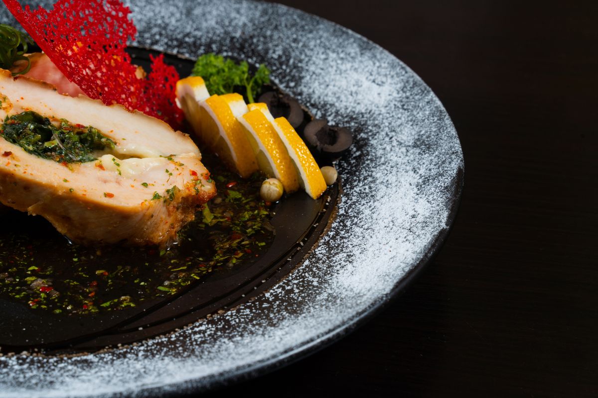 Pan-seared chicken breast garnished with fresh herbs — the golden crust that flavors the Florentine sauce