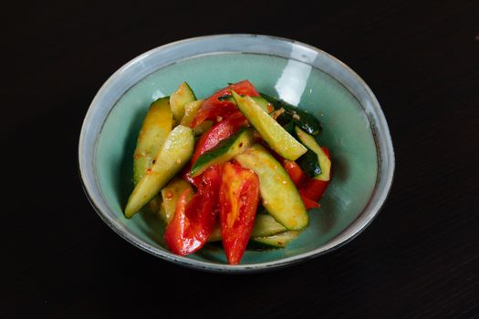 A vibrant vegetable salad featuring fresh cucumbers and tomatoes in a ceramic bowl.