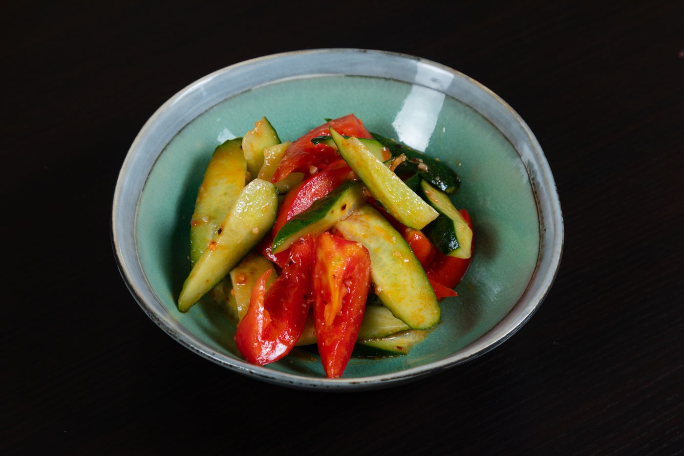 A vibrant vegetable salad featuring fresh cucumbers and tomatoes in a ceramic bowl.
