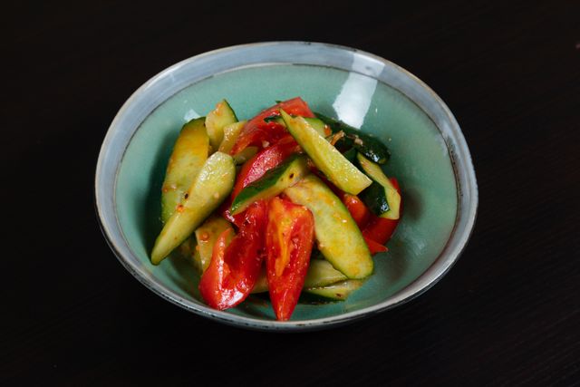 A vibrant vegetable salad featuring fresh cucumbers and tomatoes in a ceramic bowl.