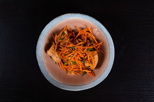 Free Top view of a savory chicken and carrot stir-fry in a ceramic bowl on a dark background. Stock Photo