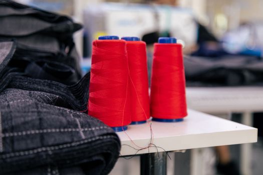 Vibrant red thread spools on a table in a tailoring room. Ideal for sewing imagery.