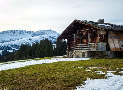 Free Rustic wooden cabin in a snowy mountain landscape with evergreen trees and beautiful winter scenery. Stock Photo