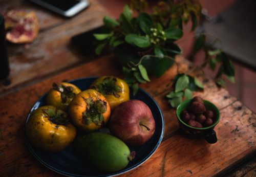 Free A rustic still life of fresh apples, persimmons, and pears on a wooden table. Stock Photo