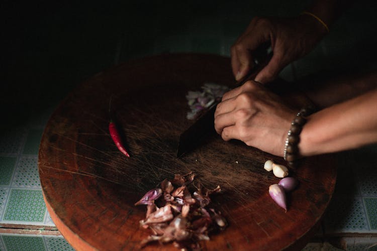 Person Cutting Onions On Wooden Chopping Board