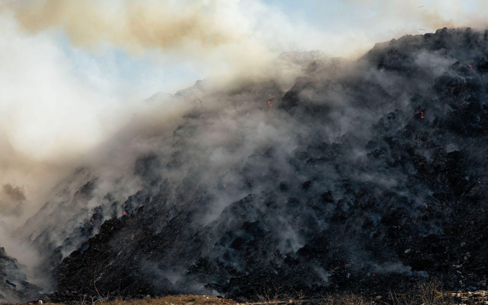 A smoky, eroded hillside with bare rock and dry brush in a rural landscape.