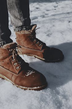 Stylish brown boots on snow-covered ground during a winter day.