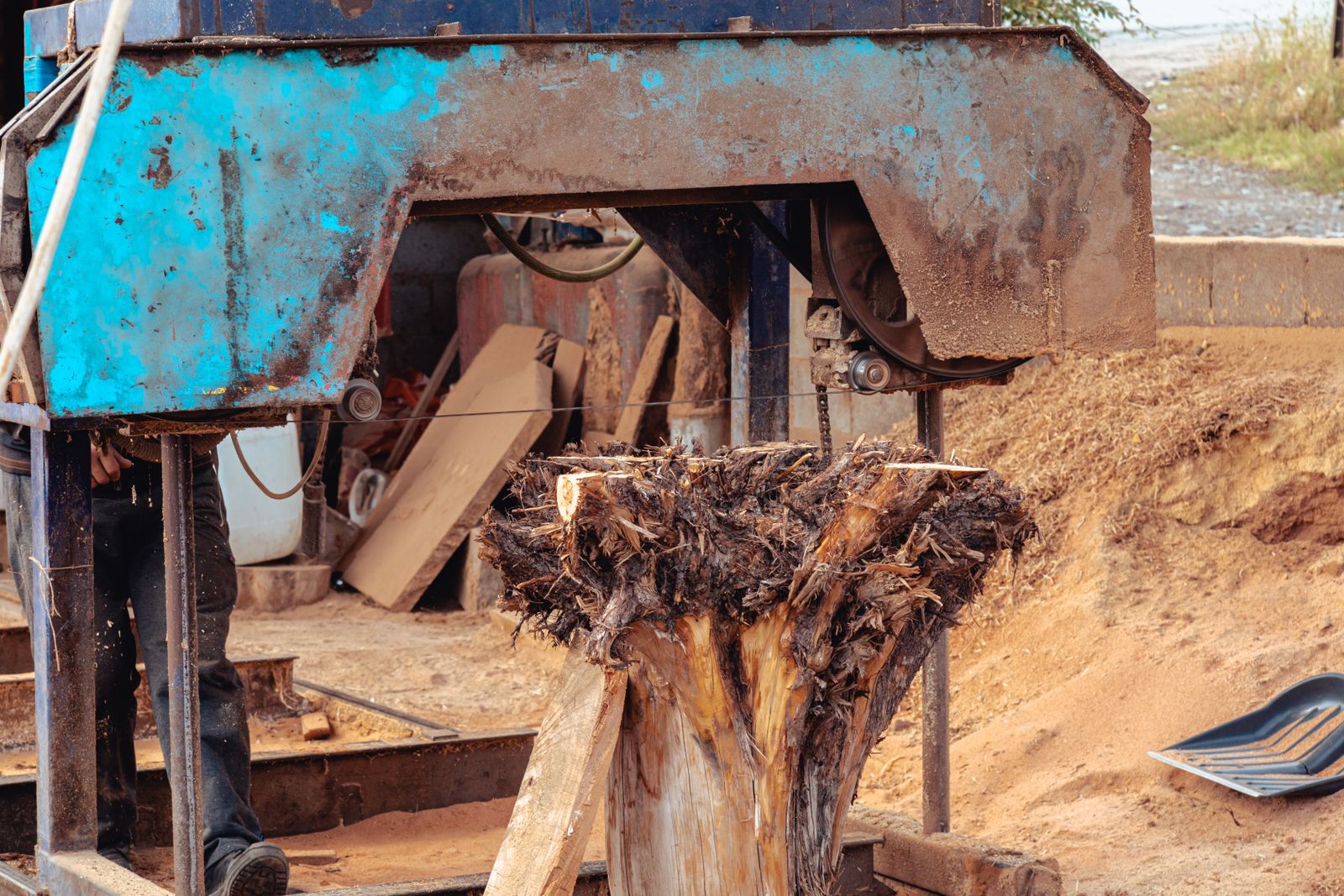 A worker milling a heavy tree trunk on a portable sawmill.