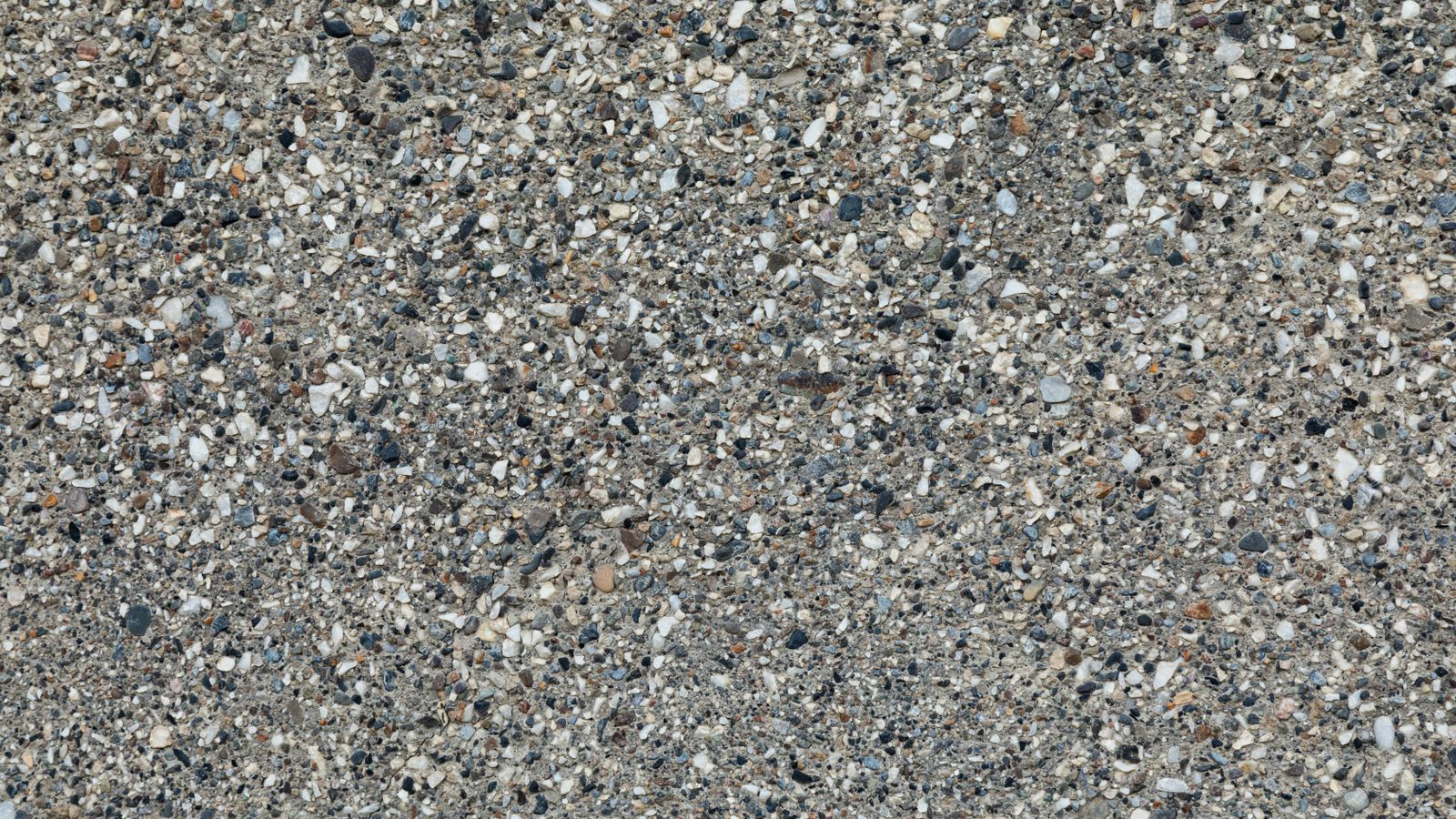 Close-up of an exposed aggregate concrete surface showing mixed natural stone