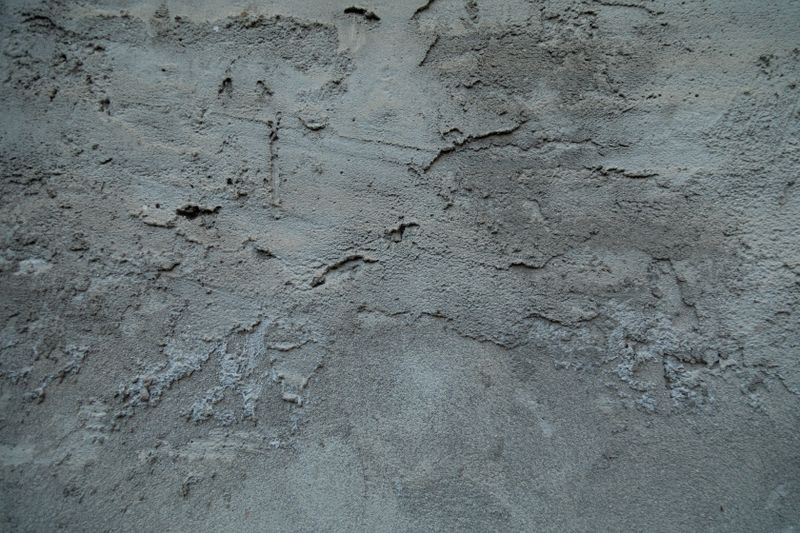 Detailed view of a textured concrete wall with cracks and rough patterns.