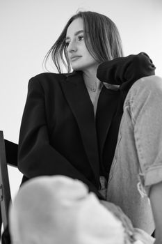 Stylish grayscale portrait of a woman in a black blazer posing thoughtfully indoors.