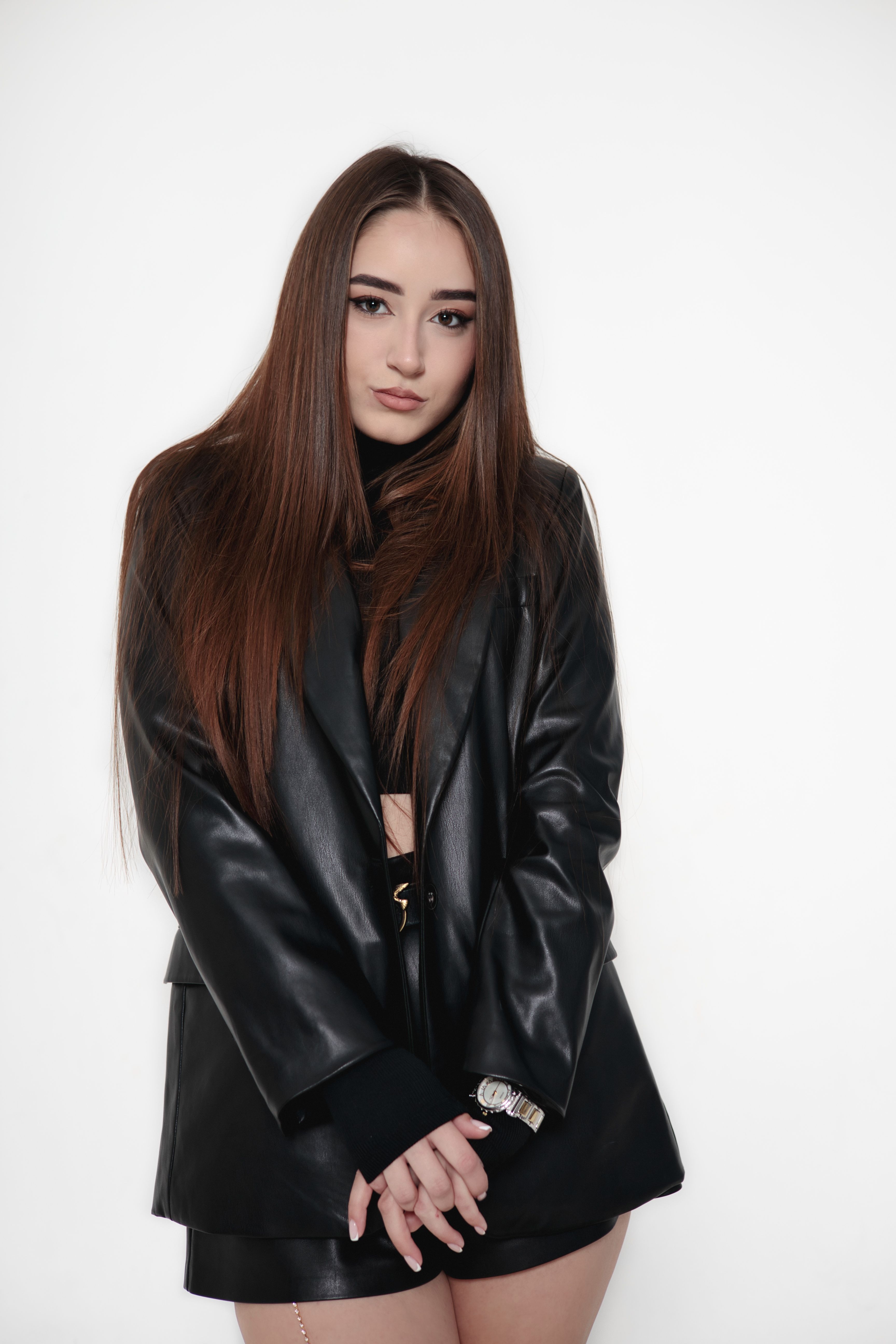 Portrait of a woman in black leather clothing against a white background.