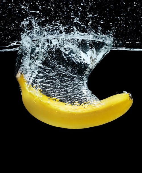 A bright yellow banana splashing into the water