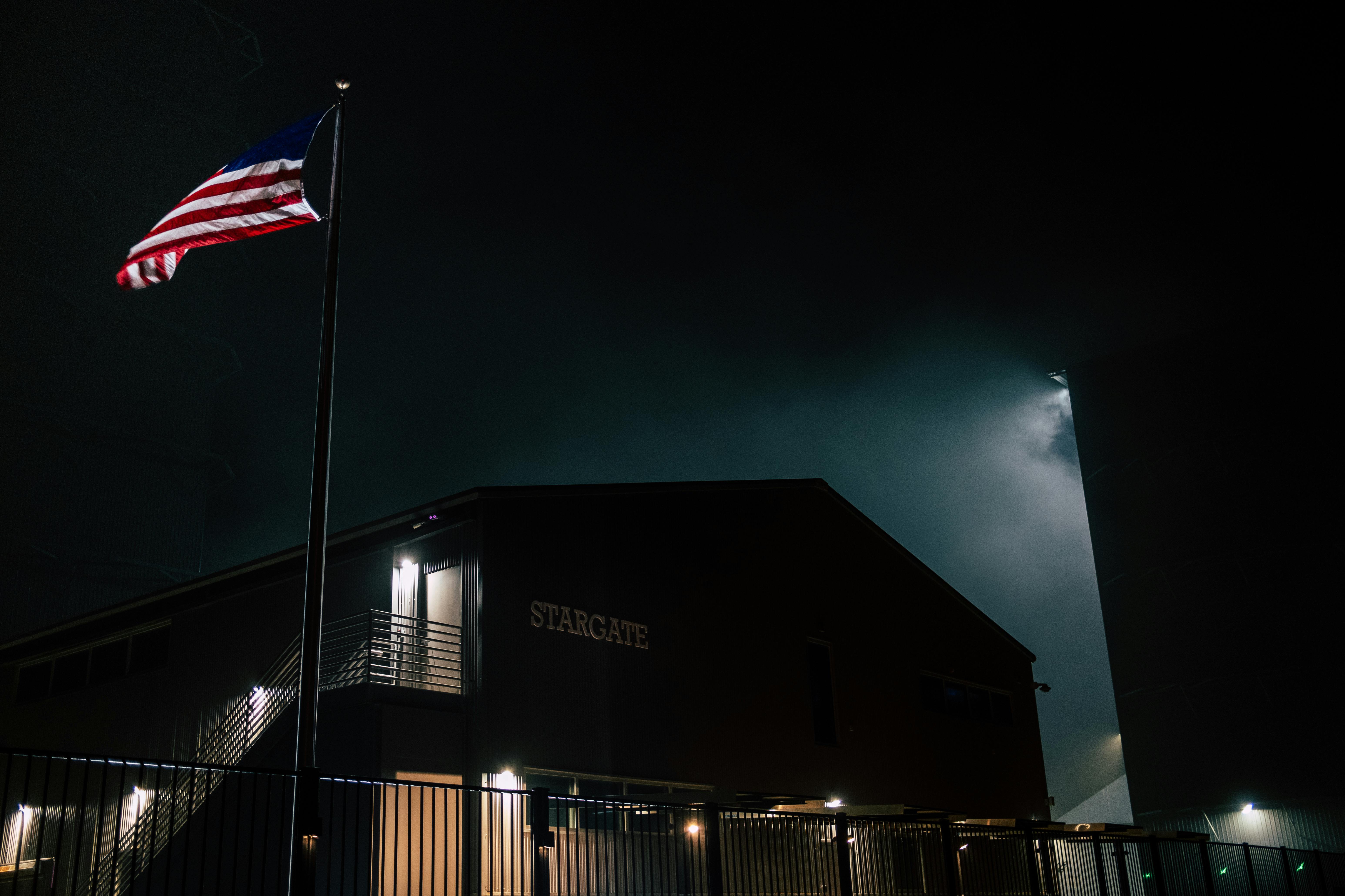 Dark atmospheric view of the Stargate building with an American flag at night.