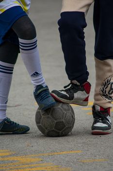 Two children in sporty attire play soccer on a street in Ankara, Türkiye.