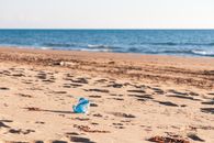 Discarded plastic bottle on sandy Pyrgos beach, Greece, highlighting environmental concerns.