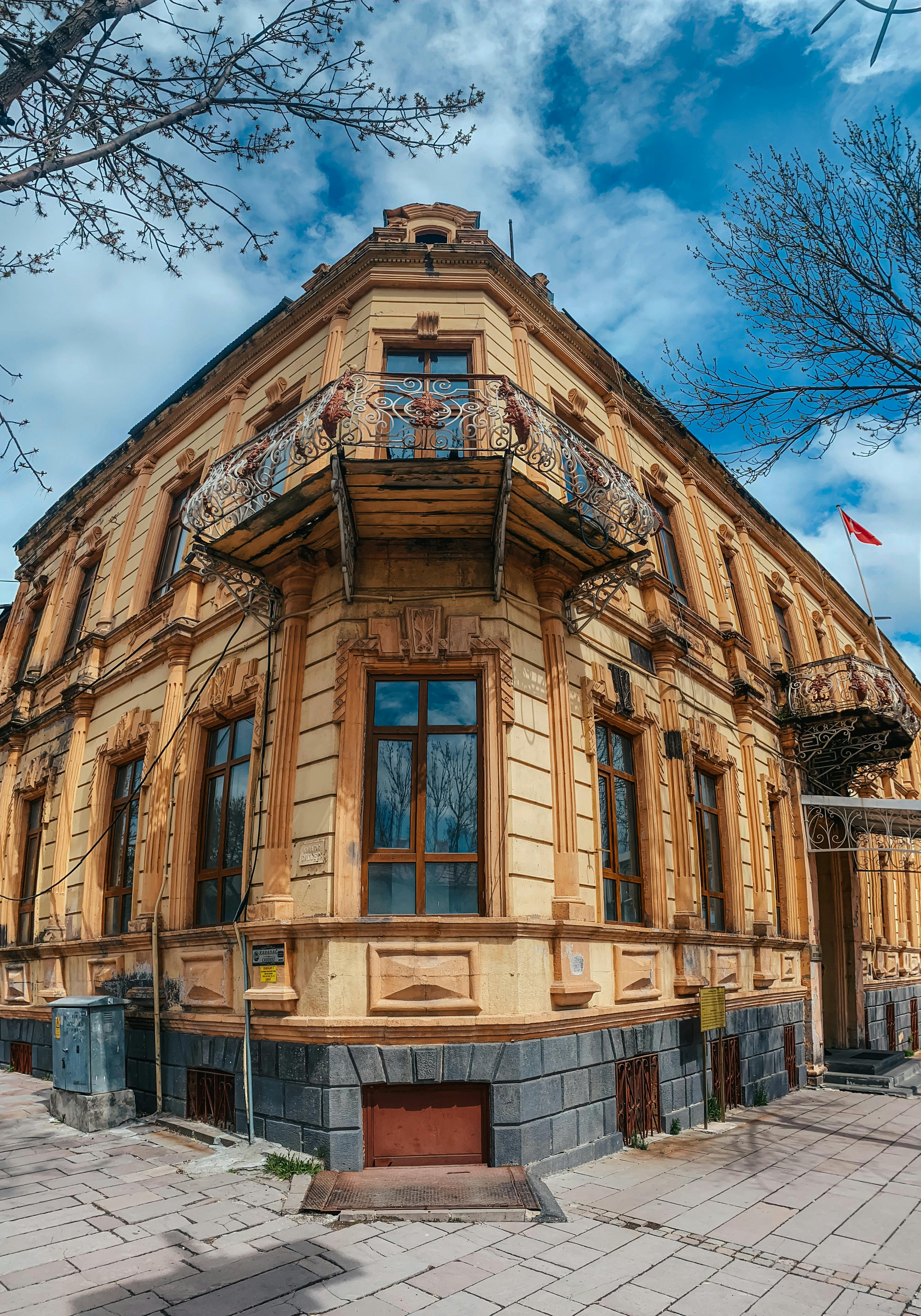 Free A vintage corner building with decorative balconies and ornate detailing, under a vibrant sky. Stock Photo