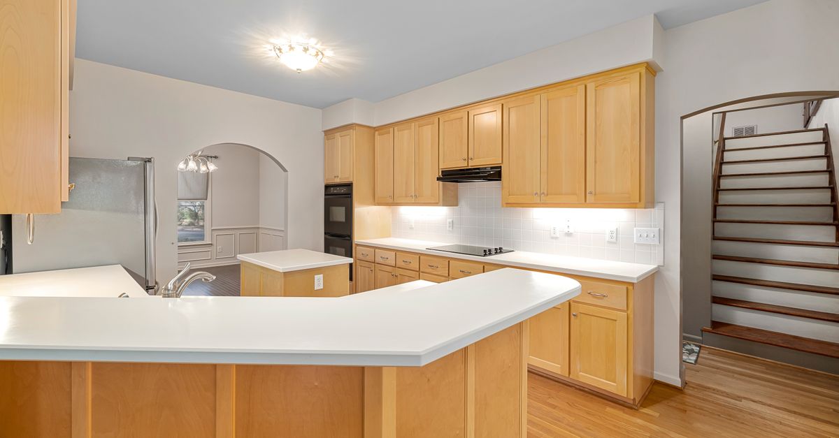 Bright modern kitchen featuring wooden cabinets, white countertops, and a central island.