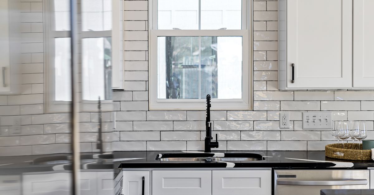 Sleek kitchen with black countertops, white cabinets, and modern design elements.