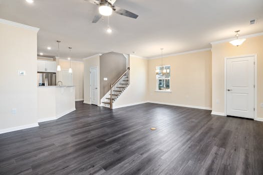 Empty modern living space with hardwood flooring and ceiling fan, ideal for new home or renovation concepts.