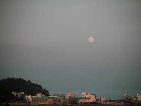 Desolate cityscape under a serene sky with a prominent full moon.