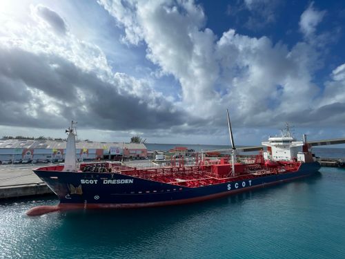 Free A large container ship docked at a vibrant harbor in Barbados under a partly cloudy sky. Stock Photo