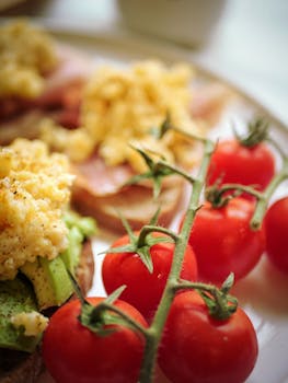 Delicious breakfast featuring ripe cherry tomatoes, scrambled eggs, and avocado on toast.