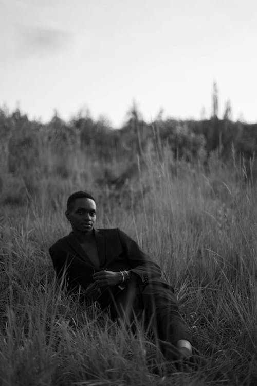 Black and White Photo of a Man in a Suit Lying on a Meadow 