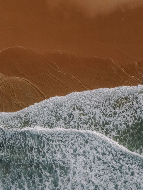 Stunning aerial capture of waves meeting golden sands on an Australian beach.