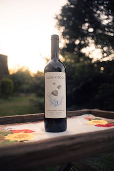 Elegant wine bottle displayed on a table outdoors at sunset, creating a sophisticated and serene ambiance.