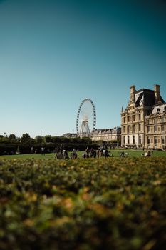 Summer day at the Louvre gardens in Paris featuring iconic Ferris wheel.