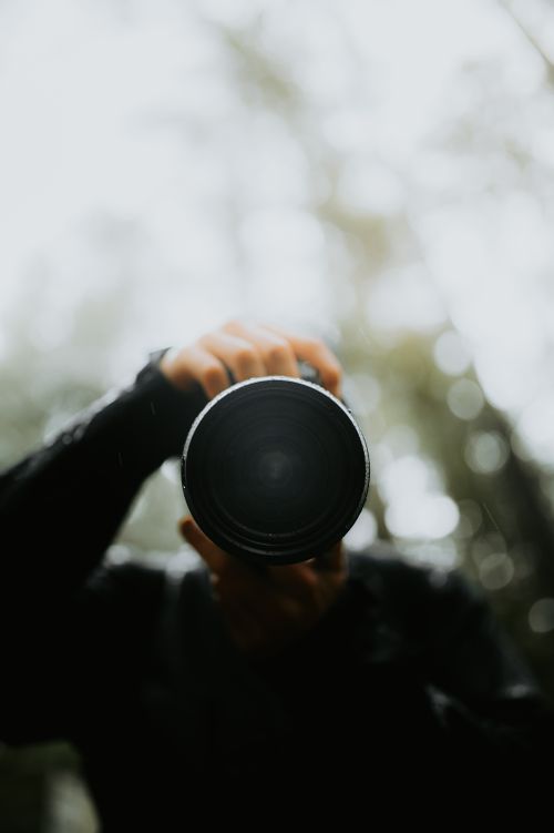 Free Captivating view of a photographer taking a shot with a camera lens in an outdoor setting. Stock Photo