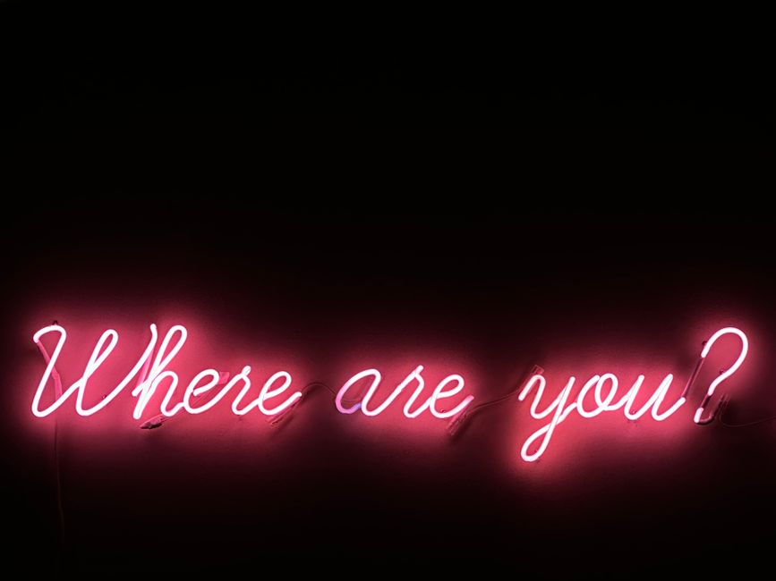 A neon sign asking 'Where are you?' glowing on a black background, creating a dramatic effect.