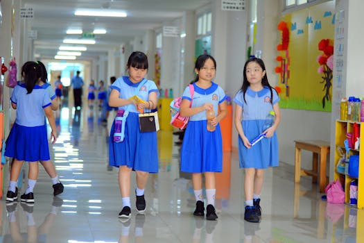 Group of schoolchildren in uniforms walking through a brightly lit hallway.