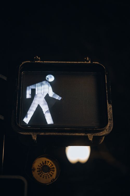 Free Close-up of a pedestrian walk sign glowing against a dark urban background. Stock Photo
