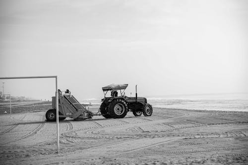 Black and White Photo of a Tractor and a Beach Cleaner on an Empty Beach 