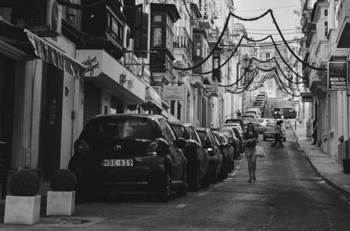 Free A captivating black and white photo of a European city street lined with parked cars and buildings. Stock Photo