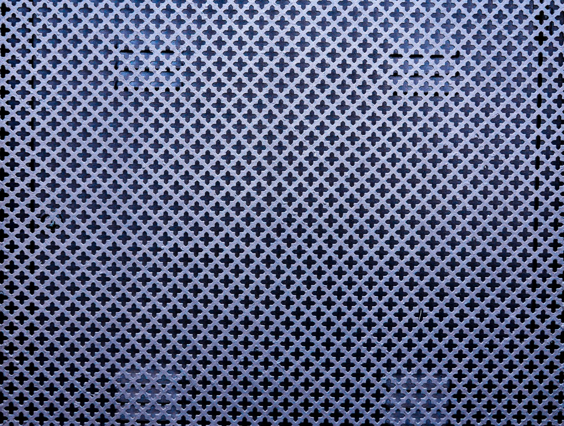 Close-up of a metal wall with intricate patterns and shapes, creating a textured abstract design.