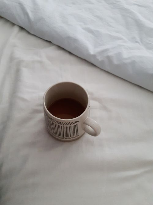 Free Ceramic coffee mug resting on a white bed, capturing a minimalist morning vibe. Stock Photo
