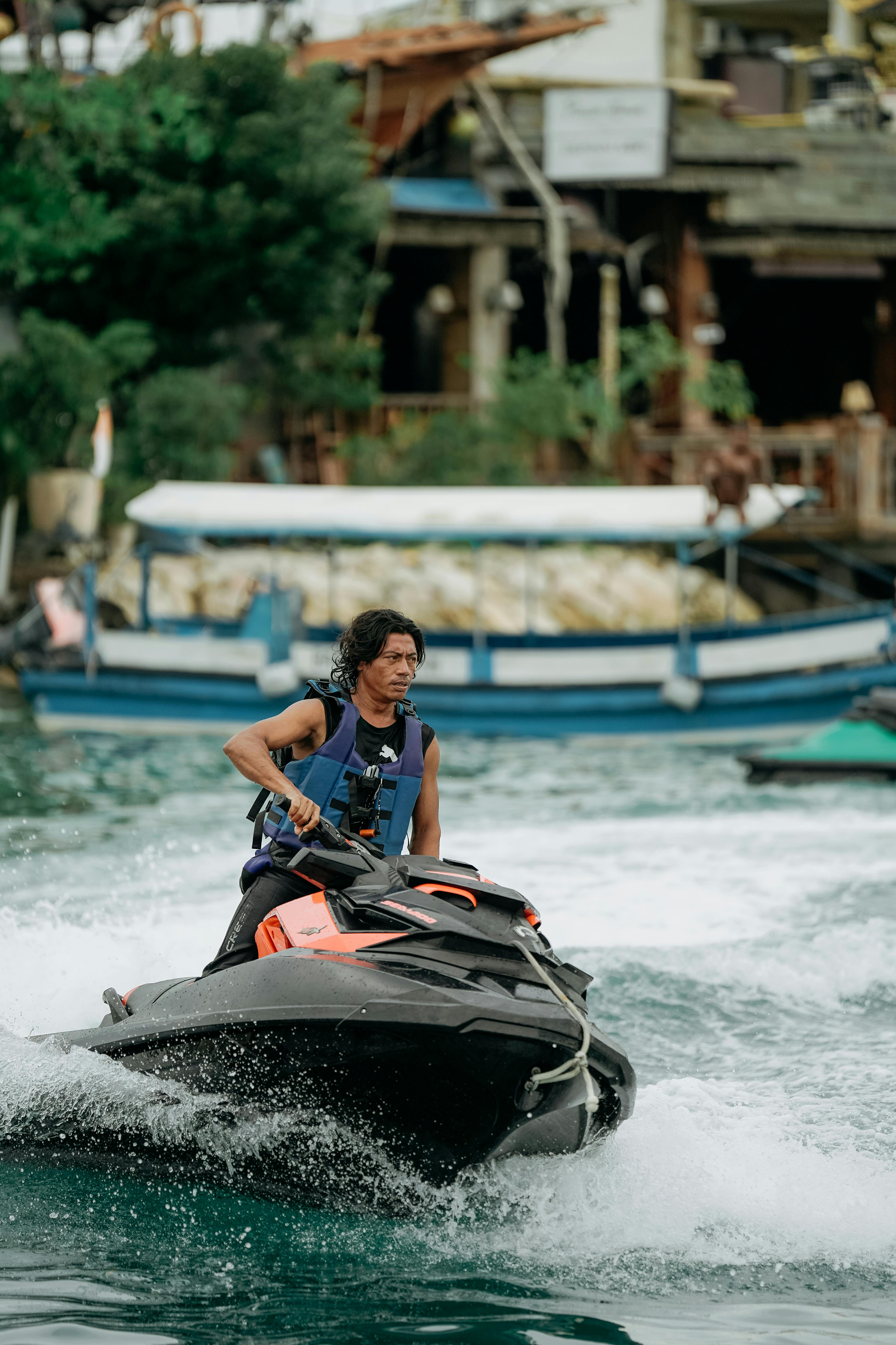 Free A man rides a jet ski on vibrant waters in Kuta Selatan, Bali, showcasing thrilling water sport action. Parasailing & Jet Ski نوسا دوا