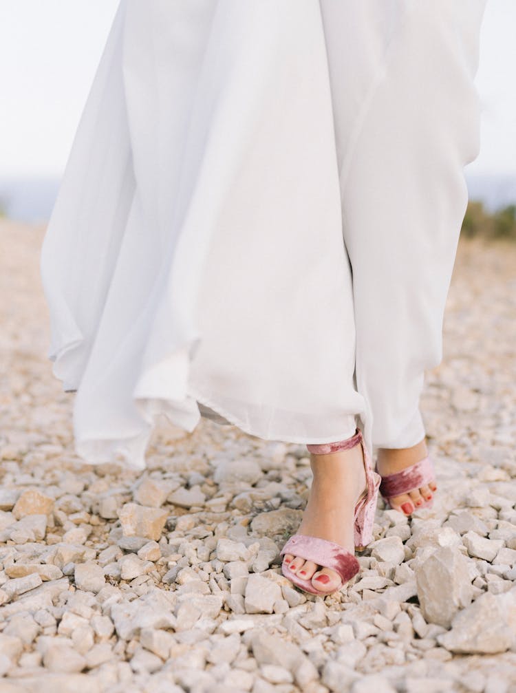 Feet Of Woman Walking On Stony Beach