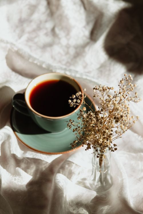 Free A stylish green coffee cup with dark brew beside dried florals on a soft background. Stock Photo