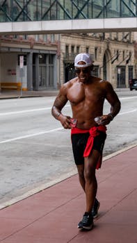 A shirtless man jogging on a city sidewalk, embodying health and fitness.