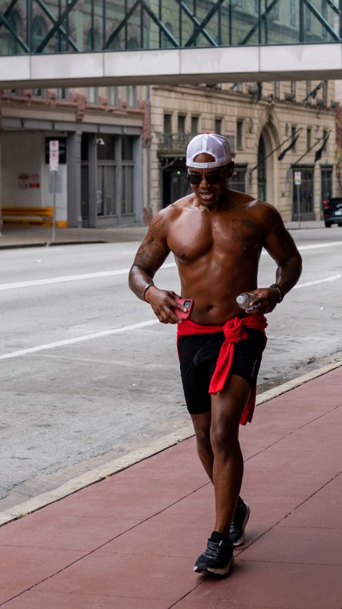 Free A shirtless man jogging on a city sidewalk, embodying health and fitness. Stock Photo