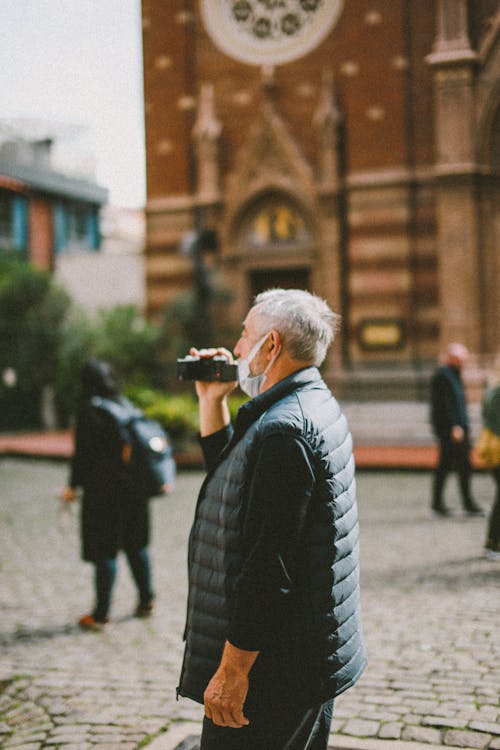 Elderly Man Holding a Camera on a Square 