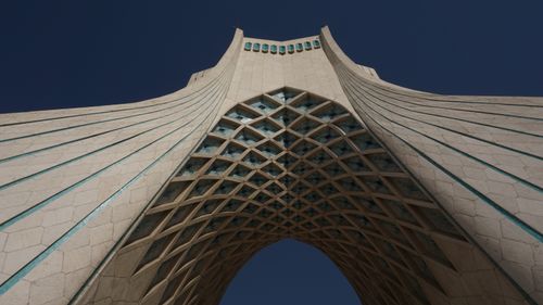 Free A dramatic low angle view of the iconic Azadi Tower under a clear blue sky in Tehran, Iran. Stock Photo