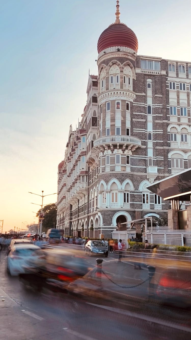 Facade Of The Taj Mahal Palace Hotel And Cars On The Street In Blurred Motion, Mumbai, India 