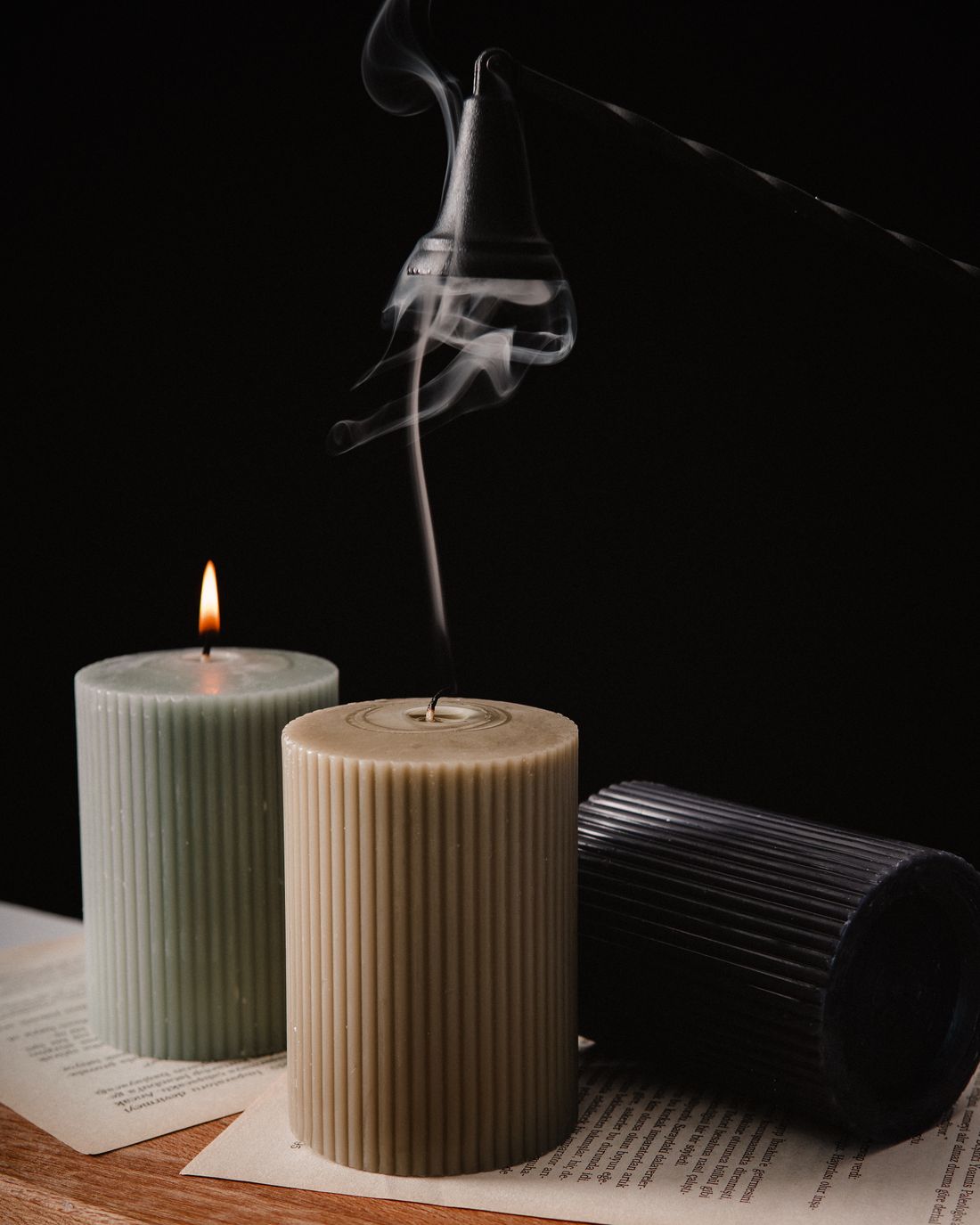 Three textured candles with smoke rising in a dark room